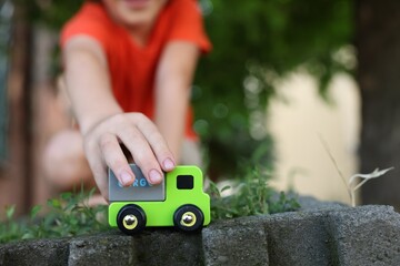 Fototapeta premium Little boy playing with toy car outdoors, closeup. Space for text