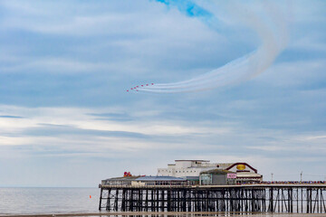 Blackpool, England - 10th August 2025: The Red Arrows performing an aerial display using red, white and blue smoke over the North Pier as part of the Blackpool Air Show