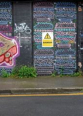 Colorful graffiti and warning sign on an urban wall during daylight in a vibrant street setting