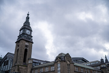 Historic clock tower stands tall against a cloudy sky in a vibrant urban setting