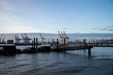 Sunset over the bustling harbor displaying cargo cranes and shipping activity near the waterfront in an urban setting