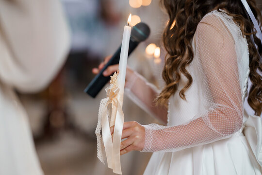Young Flower Girl Holding Lit Candle at Orthodox Christian Wedding Ceremony, White Lace Dress, Soft Lighting - Powered by Adobe