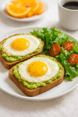 Close-up of healthy breakfast featuring avocado toast topped with fried eggs, served with lettuce and cherry tomatoes and cup of black coffee, Concept of clean eating, balanced breakfast and wellness 