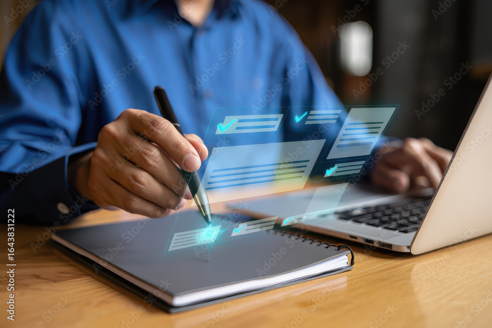 Poster person completing checklist with pen and laptop on desk in a business or office setting showing prog