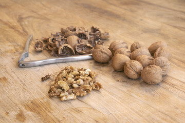 walnuts whole and cracked with shells and nutcracker on wooden cutting board
