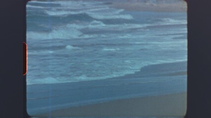 Ocean waves rolling onto sandy shore captured on retro super 8mm vintage film - Powered by Adobe