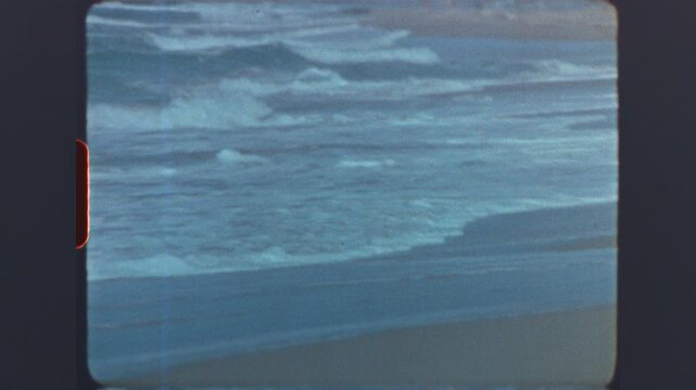 Ocean waves rolling onto sandy shore captured on retro super 8mm vintage film