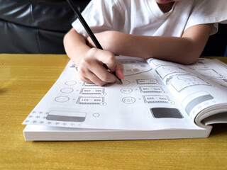 A young student sits at a wooden desk working on basic math exercises, steadily developing essential problem solving skills.