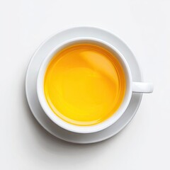 Overhead view of a white teacup and saucer filled with bright yellow tea, sitting on a white background