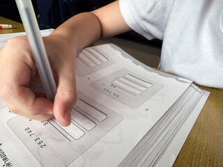 A young student sits at a wooden desk working on basic math exercises, steadily developing essential problem solving skills.