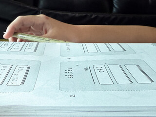 A young student sits at a wooden desk working on basic math exercises, steadily developing essential problem solving skills.