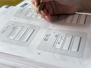 A young student sits at a wooden desk working on basic math exercises, steadily developing essential problem solving skills.