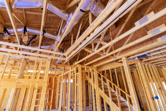 Workers are framing new building, showcasing wooden structure visible ductwork overhead during works day.