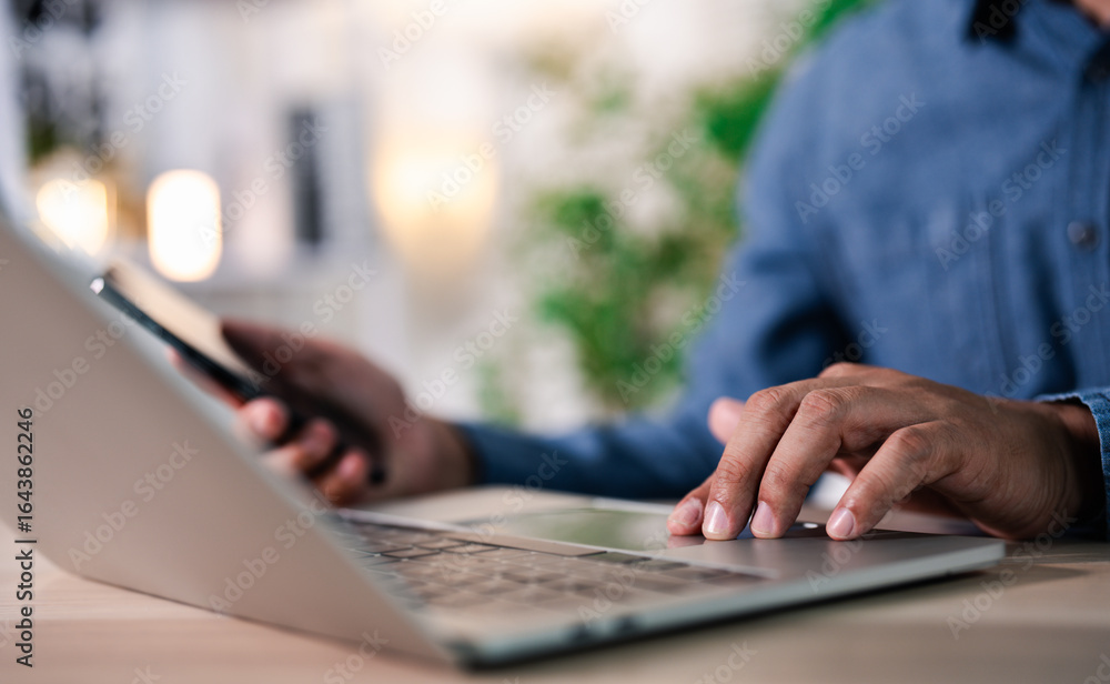 Poster close-up of hands man using laptop computer with mobile phone on office desk. workspace, businessman