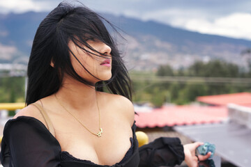 Latin woman enjoying wind on rooftop with mountain view