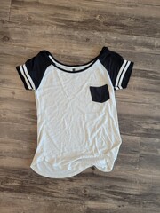 A classic white and black tshirt can be seen resting on a wooden floor