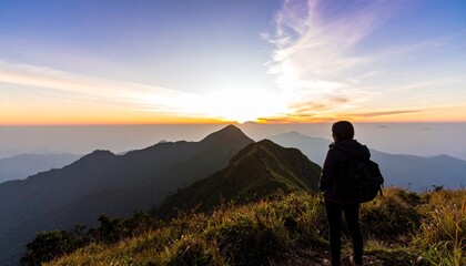 Fototapeta premium Solo adventurer standing on a mountain peak, witnessing a breathtaking sunrise over the landscape.