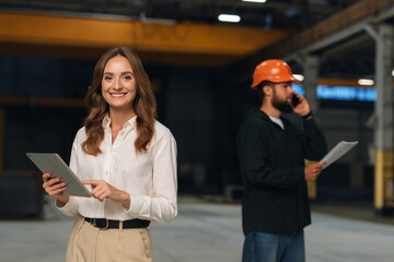 Modern Manufacturing: Confident Businesswoman with Tablet and Construction Worker Coordinating on the Phone