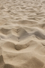 Patterns and textures of wind-sculpted sand dunes on a bright summer day. Ideal for themes related to nature, travel, and textures. Vertical photo