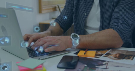 Mature man typing on silver laptop at office desk, with digital HUD icons, sticky notes, smartwatch