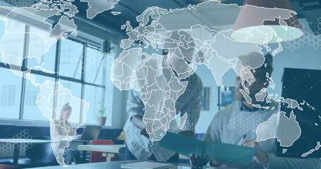 Collaborating coworkers reviewing document at office desk, with laptop notepad world map overlay