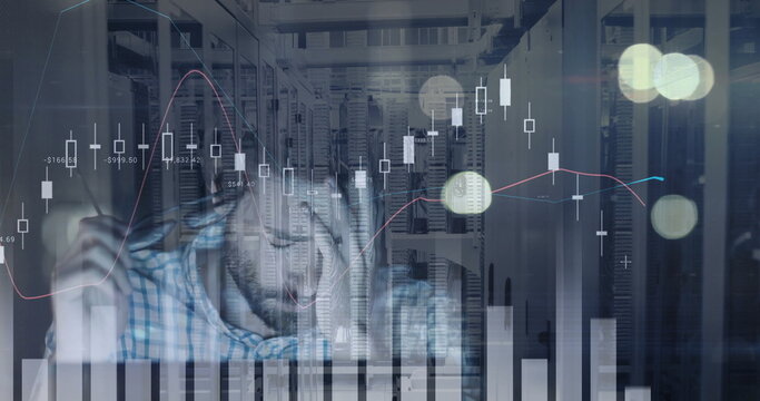 Analyzing engineer wearing plaid shirt taking notes at server room desk, with bar charts