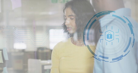 Reviewing professional in yellow shirt studying notes on glass wall in office, with padlock icon