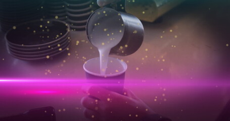 Pouring barista hand guiding metal pitcher filling paper cup at cafe counter, with neon pink light
