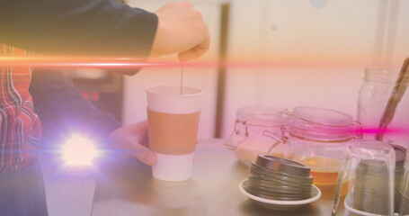 Stirring barista hands mixing coffee in paper cup on café counter, with lids, glass jars, sticks