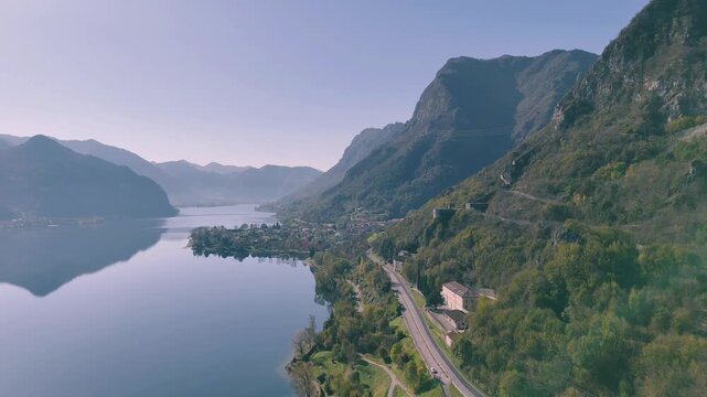 Drone scenery of tranquil lake Idro surrounded by large, tree-covered mountains and Rocca d'Anfo