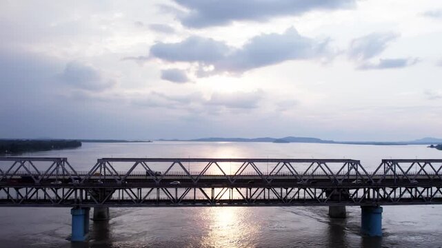 Saraighat Bridge spans Brahmaputra River with the sun reflecting off the water