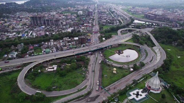 view over Bhangagarh with a multi-level highway, a pond, and distant mountains under a cloudy sky