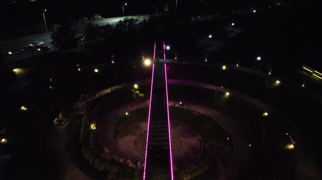 the women's walk in the fundidora park, glowing with purple, yellow neon lights at night near road