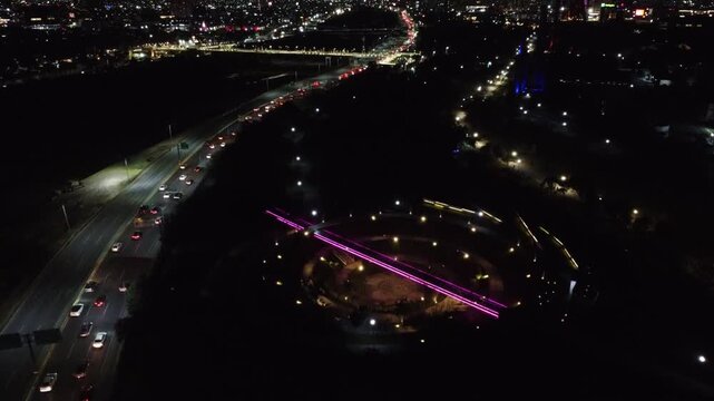 The women's walk in the fundidora park, glowing with purple, yellow neon lights at night near road