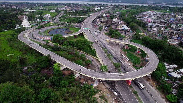 Jalukbari Flyover Bridge with pond, surrounded by green spaces, buildings and waterbody in distance