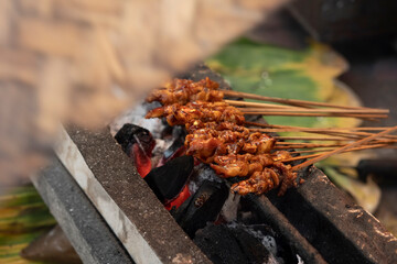 Indonesian traditional grilled chicken satay (sate ayam). Southeast Asian street food, grilled chicken dishes, delicious food, culinary culture. Chicken satay on traditional charcoal fire.