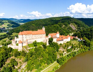 Obraz premium Aerial view of a medieval castle nestled on a hillside overlooking a valley and river