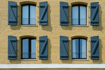 Fototapeta premium Close up of four windows with Z shaped shutters on yellow facade in Copenhagen CPH