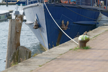 Metal ship moored in port with anchors and bumper pads