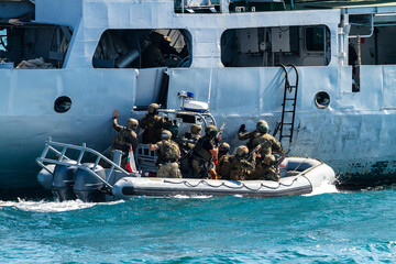 Military soldiers boarding ship for control and search for refugees on ship deck during operation...