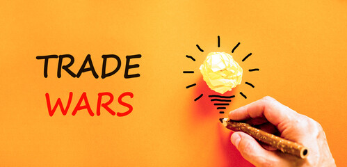 Trade wars symbol. Concept word Trade wars on beautiful orange paper. Businessman's hand. Light...