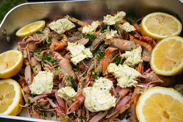 Steel searing pan with virgin lobster, garlic butter, citrus and homegrown herbs, on the side of a hot grill waiting to be prepared, at a luxury gathering.