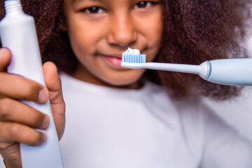 Healthy teeth, toothpaste. Small girl, toothbrush. Multiracial girl brushes her teeth an electric toothbrush. Little girl toothbrush closeup. Little cute african american girl brushing her teeth