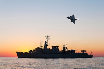 A military plane flies over a warship during a peacekeeping operation in the Black Sea.  © ValStock
