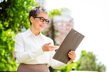 Professional woman reviewing work documents outdoors in business attire in a vibrant urban setting