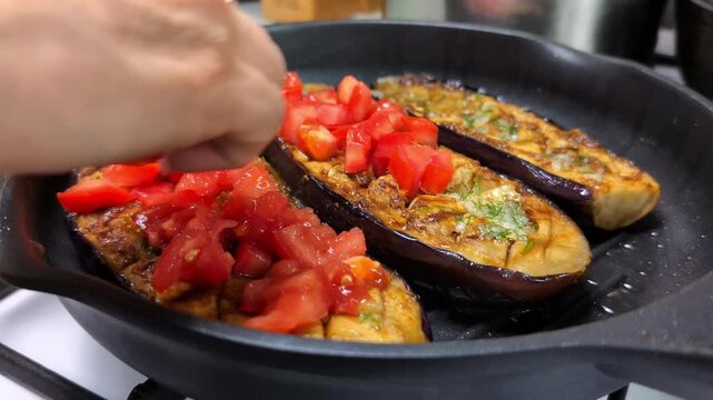 Juicy tomato cubes hitting charred eggplant with garlic and thyme in cast-iron skillet &ndash; crispy sound on