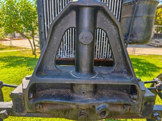 The front of a vehicle has a black frame and a black radiator. The radiator is attached to the frame with bolts