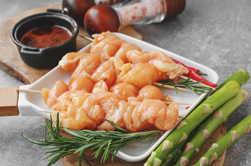 Raw turkey breast kebab. Raw cut turkey breast on wooden skewers with asparagus and sauce is ready...