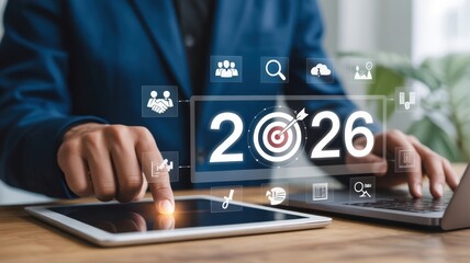 Business Goals - A businessman's finger touching a tablet with a "2026" text and a target icon, surrounded by other business icons, for future planning