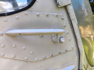 A white airplane door with a metal handle. The handle is rusted and has a few screws